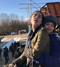 a woman holding a child in her arms while standing next to a building under construction