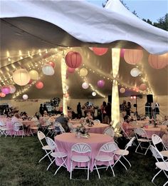 tables and chairs are set up under a tent with paper lanterns hanging from the ceiling