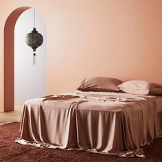 a bed in a room with an arch on the wall and a lamp hanging above it