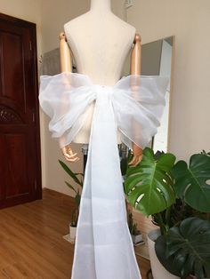 a mannequin with a white bow on it's back in front of a mirror