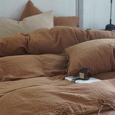 a bed with brown linens, pillows and a jar of essential oils on it