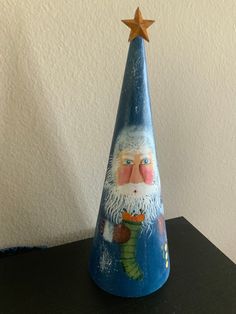 a blue christmas cone with a santa clause on it and a star in the top