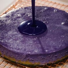 a purple cake sitting on top of a cooling rack