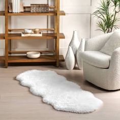 a living room with white furniture and a rug on the floor in front of a bookshelf