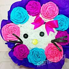 a paper plate that has flowers and a cat face on the top, with a bow around its neck