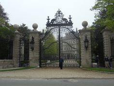 a man standing in front of a gate that is surrounded by stone pillars and wrought iron gates