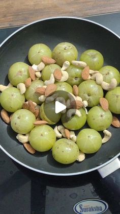 green olives and almonds in a frying pan on top of an electric stove