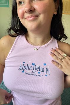 a woman wearing a pink tank top is posing for the camera with her hand on her chest