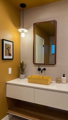 a bathroom with a sink, mirror and lights on the wall above it's counter