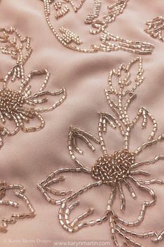 an embroidered fabric with beading and flowers on the side, in light pink color