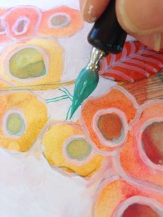 someone is using a pen to draw circles on paper with watercolors and colored pencils