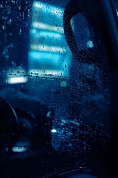 rain is falling on the windshield of a car as it sits in front of a building