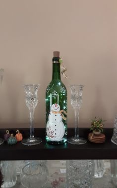 there is a bottle with a snowman on it and wine glasses next to it