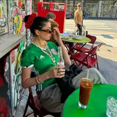 a woman sitting at a table with a drink in her hand