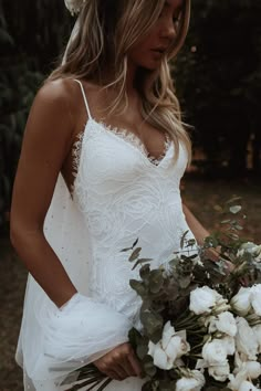 a woman in a white dress holding a bouquet of flowers and wearing a flower crown