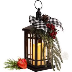 a lantern with a christmas decoration hanging from it's side and pine cones on top