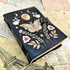 an open book with flowers and butterflies on it sitting on top of a piece of paper