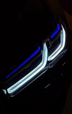 the front end of a black car with blue lights on it's grilles