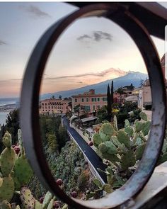 a view through a round metal object looking at a town and ocean in the distance