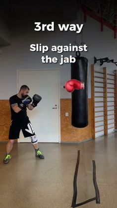 a man in black shirt and shorts standing next to punching bag with words on it