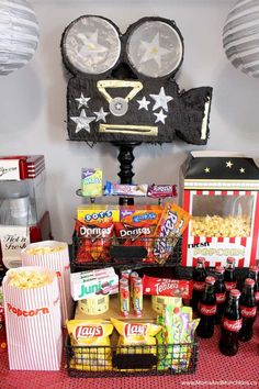 an assortment of snacks and drinks on a red tablecloth with paper lanterns hanging from the ceiling