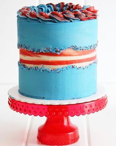 a blue cake with red, white and blue frosting on top sitting on a stand