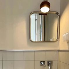 a bathroom with a sink, mirror and toilet paper dispenser in it