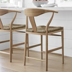 two wooden chairs sitting on top of a hard wood floor next to a white counter