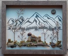 a wooden frame with rocks and plants in it