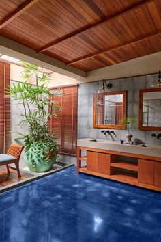 a bathroom with a large blue floor and wooden walls, along with a plant in the corner