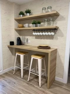 two wooden stools sit in front of a counter with shelves on the wall behind them