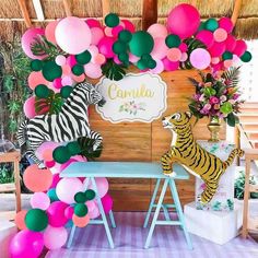 a table topped with balloons next to a wall covered in pink, green and white balloons