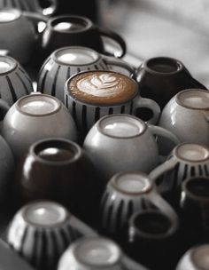 there are many black and white vases with coffee in them on the table together