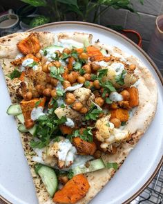 a white plate topped with a pizza covered in veggies and chickpeas