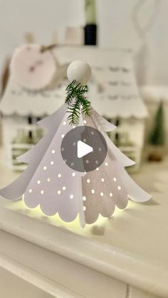 an origami christmas tree with white lights on it's top and green leaves