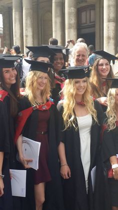 a group of people standing next to each other in graduation gowns and caps on