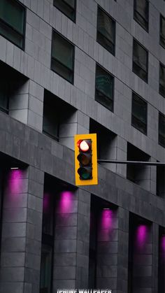 a traffic light hanging off the side of a building with purple lights on it's sides