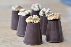 small chocolate cones with walnuts on top sitting on a wooden table, ready to be eaten