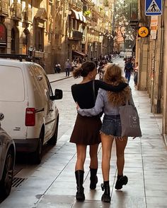 two women walking down the street with their backs to each other and one holding her arm around another woman's shoulder