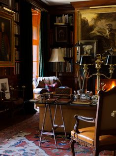 a living room filled with lots of furniture and bookshelves covered in paintings on the walls