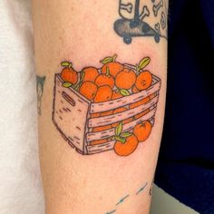 a tattoo with oranges in a wooden crate