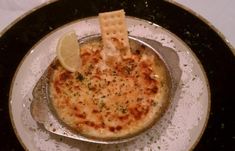 a bowl of food with crackers and cheese on the side sitting on a plate