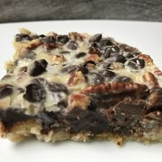 a close up of a piece of cake on a plate with chocolate chips and nuts