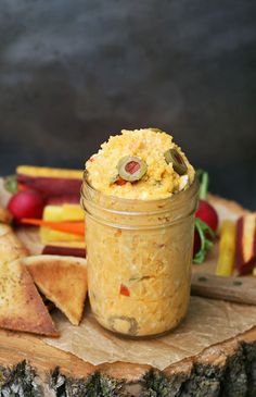 a glass jar filled with food sitting on top of a wooden table next to crackers