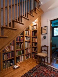 a room with stairs, bookshelves and a rug on the floor in front of it