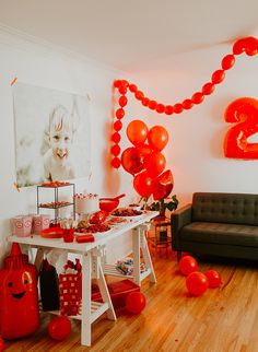 a table with red balloons and decorations in a room decorated for a birthday or baby's first birthday