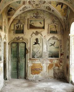 an old room with paintings on the wall and doors to another room that is empty