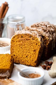 a loaf of pumpkin spice bread on a plate with cinnamons and spices around it