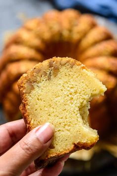 a person holding a piece of bread in front of a bundt cake