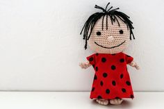 a crocheted doll wearing a red dress and black dots on it's body